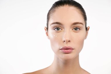 Kamera, yanağına Krem noktalar bakarak mükemmel yüz cilt ile esmer kadın 