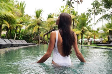 Bir lüks resort, güzel bir kadını rahatlatır süre yüzme ve havuz başında şezlong üzerinde. Kavramı: seyahat, tatil, dinlenme, otel.