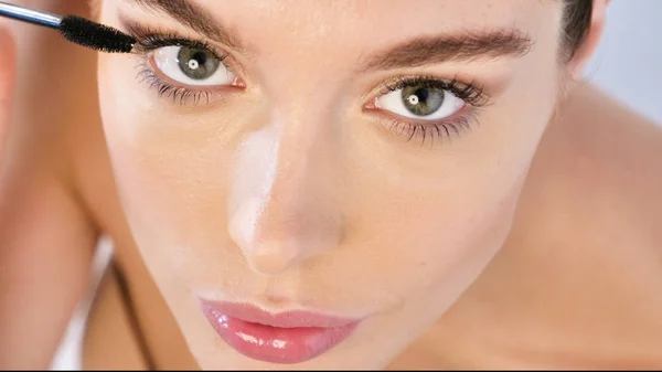 close up portrait of woman with perfect face skin and make up, applying mascara