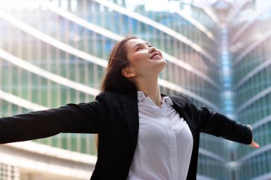 Bir takım elbise giymiş bir iş kadını, kollarını gökyüzüne yükseltir ve özgürlük ve başarı çalışmasında bir işareti olarak nefes.