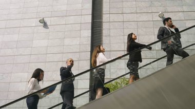 Bir grup iş adamları, farklı etnik gruplardan ofisleri gökdelen içinde girmek için yürüyen merdiven tırmanmak. Kavramı: takım çalışması, önlem ve başarı.