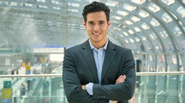 Ararken, bir inşaat arka planda gülümseyen genç bir yakışıklı işadamı takım, istasyonda portresi. Konsept: yeni iş, iş ilişkileri, kariyer büyüme, başarı.