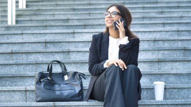 Gülümseyen, mutlu, genç güzel iş kadın öğrenci takım, merdiven, merdiven, plastik bardak, çanta, evrak çantası'nı kavramı yeni iş, iletişim, kahve Arap, gözlük Evet oturan