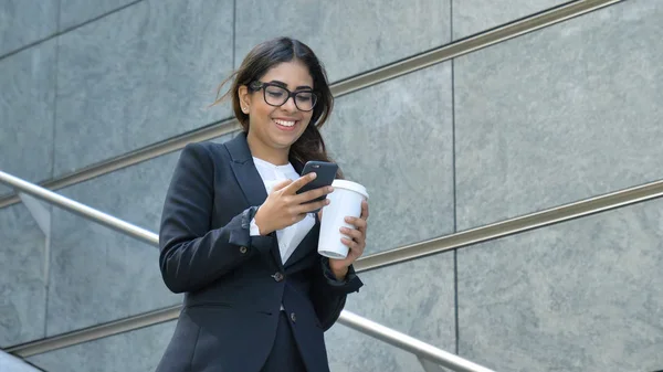 スーツの若い美しいビジネス女性 は笑顔 Cofee サクと階段を下りる 携帯電話を使用して メッセージを書き込みます コンセプト 新しいビジネス コミュニケーション アラブ — ストック写真