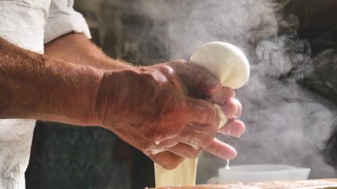 Ev yapımı peynir üreticisi, sabahları inek koyunlarından taze süt ile el yapımı mozzarella üretiyor. Gelenek kavramı: İtalya, mozzarella.