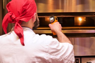 Profesyonel pizza şefi adam pizza ile odun fırında sıcaklık kontrol geri görünümü
