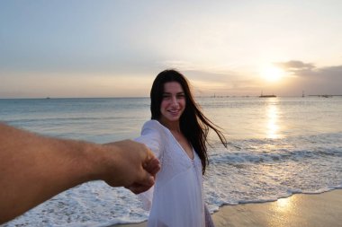 gülümseyen Güzel genç kadın deniz suyunda gülümsüyor ve erkek elini tutarak 