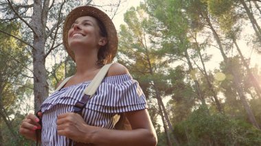 Güneşli bir günde, bir güzel genç turist (kız), hasır şapkalı bir sırt çantası ile bir portresini orman, arka plan ağaç yürür. Konsept: eğlence, güzel manzara, spor, seyahat.