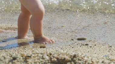 Bir anne ilk adımları küçük bebeği sahilde adım adım yapar tatile yenidoğan yürümeyi öğrenir...