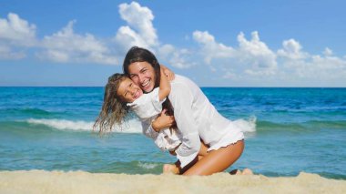 Anne ve kızı mutlu oynarken denizde, gülümseyen, deniz mavi su arka plan beyaz giysili sarılma.