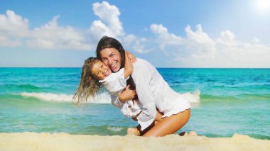 Anne ve kızı mutlu oynarken denizde, gülümseyen, deniz mavi su arka plan beyaz giysili sarılma.