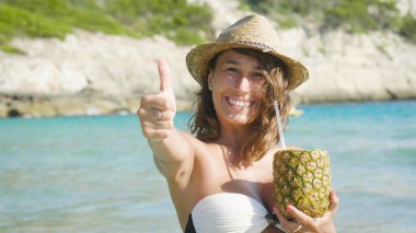 yaz tatili sahilde zevk ve başparmak yukarıya el hareketi sırasında taze ananas suyu tutan kadın