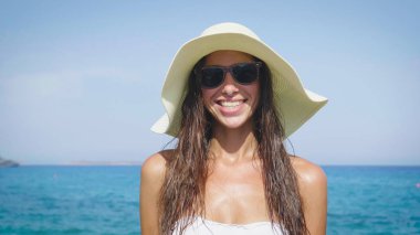 Denizde bir mayo, beyaz hasır şapka, üzerinde deniz ve kum arka plan güneşlenme güzel bir genç kadının portresi. Kavram deniz, özgürlük, Güneş, seyahat, dalgalar, tatiller, özgürlük, zevk, yaz saati.