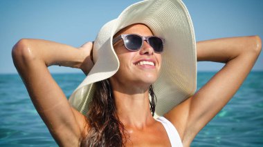 Güzel kadın, su, banyo Bayan mayo beyaz şapkalı gülümseyen ve güneş gözlüğü takıyor