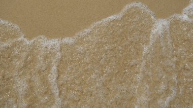 Kahverengi kum, dalga dalga arka tarafından yıkanmış. Konsept: dinlenme, deniz, plaj, deniz kenarı, ses dalgaları, özgürlük.