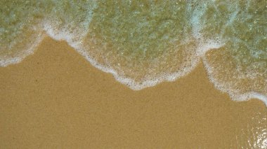 Kahverengi kum, dalga dalga arka tarafından yıkanmış. Konsept: dinlenme, deniz, plaj, deniz kenarı, ses dalgaları, özgürlük.