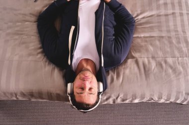 Yatakta yatan bir adam kablosuz kulaklık ile müzik dinler ve rahatlatır. Adam dansları ve hayalleri ile müzik. Kavramı: müzik, gevşeme, rüya.
