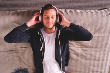 Yatakta yatan bir adam kablosuz kulaklık ile müzik dinler ve rahatlatır. Adam dansları ve hayalleri ile müzik. Kavramı: müzik, gevşeme, rüya.