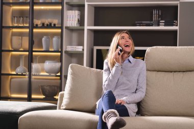 Bir kadın kanepe, bir ileti gönderir ya da ile belgili tanımlık telefon ve gülümsüyor çağırır. Kavramı: sosyal ağ, mesaj, teknoloji.