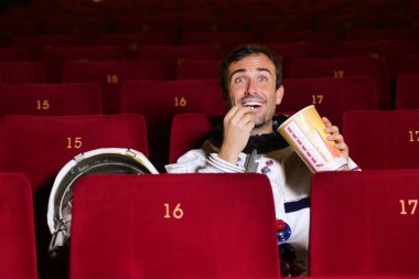 Astronot bir film pop mısır yemek ve film zevk görünüyor. Kavramı: sinema ve uzay filmleri, film diğer dünya, gerçeküstü durumlar.