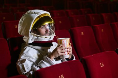 Astronot bir film pop mısır yemek ve film zevk görünüyor. Kavramı: sinema ve uzay filmleri, film diğer dünya, gerçeküstü durumlar.