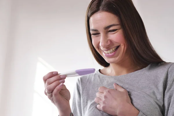 A beautiful woman takes a pregnancy test and as soon as she reads that she is pregnant, she explodes in a moment of happiness and joy for the future birth of her child. Concept of: birth, life, family