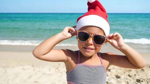 Uma Menina Está Divertindo Brincando Mar Chapéu Papai Noel Maiô — Fotografia de Stock