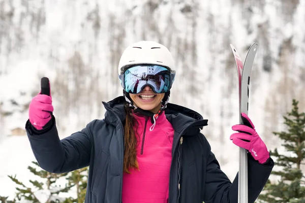 Portrait of a smiling skier on vacation in the mountains, behind her you can see the snow-covered mountain. Concept of: holidays, sport, passion, mountain.