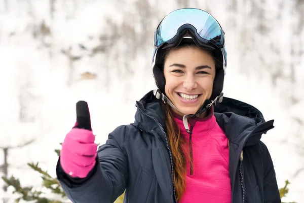 Portrait of a smiling skier on vacation in the mountains, behind her you can see the snow-covered mountain. Concept of: holidays, sport, passion, mountain.