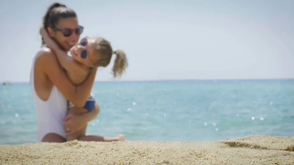 The best moments, the mother with a small daughter embraces on the sea, in swimsuit, rest in beautiful weather, sea and sand background. Concept: love, lifestyle, children, vacations, kids, summer.