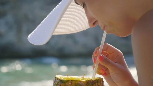 ストローでパイナップルを押し フレッシュ ジュースを飲みながらビーチで夏休みを楽しんでいる女性の画像をトリミング — ストック写真