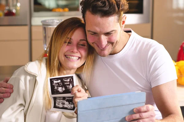 一对恋爱中的已婚夫妇用平板电脑对父母进行视频拍摄 宣布儿子的出生 展示超声波 — 图库照片
