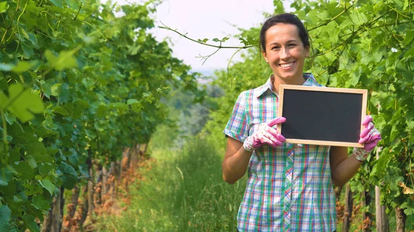 Счастливая Улыбающаяся Фермерша Стоящая Пустой Доской Виноградной Плантации — стоковое фото