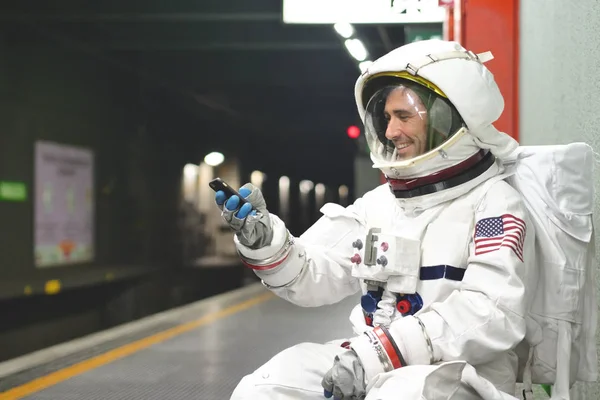 An astronaut dressed man uses the smartphone to call and send messages. The astronaut smiles while looking at the phone in his hand. Concept of: Phone Promotions, Messages and Spatial Calls.