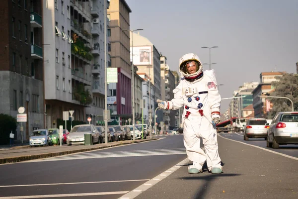 A man dressed as astronaut after losing hitchhiking on a city street. Concept of: adventure, hitchhiking, travel applications, surreal, space travel.