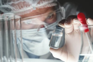 Fütüristik bir doktor, cerrah, teknolojik bir dijital holografik tabak, tıbbi maske, bir kap, kahverengi gözleri inceliyor. Konsept: futuristik tıp, yeni teknolojiler, doktorlar, laboratuvar, gelecek.