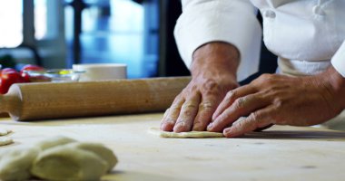 bir şef elinde oklava pizza hamuru ve tatlı İtalyan lezzeti ve geleneksel İtalyan mutfağı ile profesyonel bir mutfakta İtalyan tarzı yoğurun .