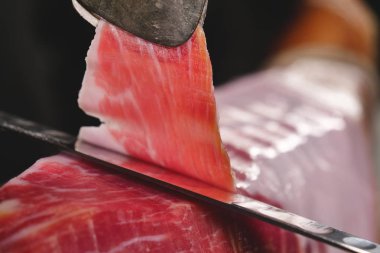 Makro bir dilim jambon, mükemmel kalitede, geleneğe göre bıçakla kesen bir şefin kapatın. Jambon, kavramı gıda, İspanya ve İtalya, yemek tedarik.