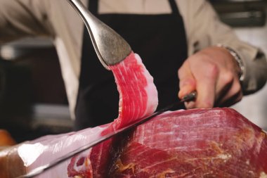 Makro bir dilim jambon, mükemmel kalitede, geleneğe göre bıçakla kesen bir şefin kapatın. Jambon, kavramı gıda, İspanya ve İtalya, yemek tedarik.