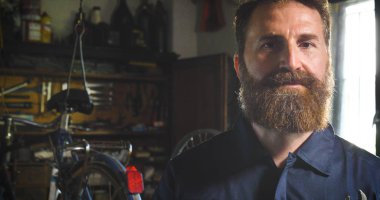 Anahtarı bir başarılı su kuyusu-damat yakışıklı sakallı ana hipster portresi, Bisikletler, onun atölye, tekerlekler, çerçeve, bir bisiklet tamiri uzman. Konsept: pro bisiklet, döngüsü tutku, yaşam biçimi.