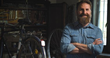 Anahtarı bir başarılı su kuyusu-damat yakışıklı sakallı ana hipster portresi, Bisikletler, onun atölye, tekerlekler, çerçeve, bir bisiklet tamiri uzman. Konsept: pro bisiklet, döngüsü tutku, yaşam biçimi.