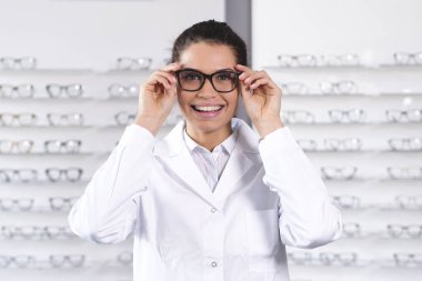 mutlu gülümseyen kadın gözlük gözlük ayarlama ve kameraya bakarak optik Merkezi