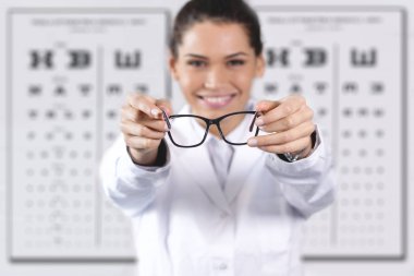 Snellen görme testi ve gözlük vererek keskinliği için kullanılan grafik ayakta optik Center'da mutlu gülümseyen kadın 