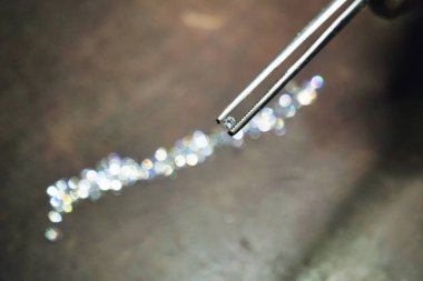 Kim profesyonel cımbız ile el yapımı lüks mücevher üretimi için kullanacağı elmas denetler bir kuyumcu el kapatın. Kavramı: gelenek, lüks, takı.