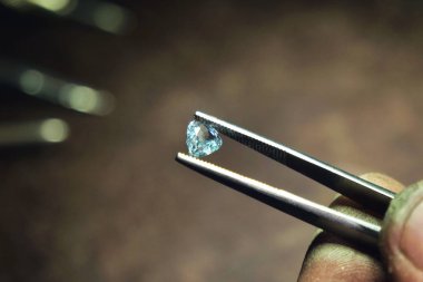 Kim profesyonel cımbız ile el yapımı lüks mücevher üretimi için kullanacağı elmas denetler bir kuyumcu el kapatın. Kavramı: gelenek, lüks, takı.