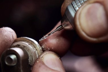 Close up of a goldsmith's hand making a gold or silver ring or a diamond using goldsmith's tools. For this work it takes precision and patience. Concept of: tradition, luxury, jewelry. clipart