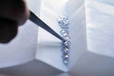 Kim profesyonel cımbız ile el yapımı lüks mücevher üretimi için kullanacağı elmas denetler bir kuyumcu el kapatın. Kavramı: gelenek, lüks, takı.