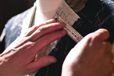 Mezura kullanarak takım elbise dikerken bir terzinin portresi. Konsept: Moda, terzilik, dükkan