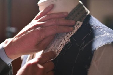 Mezura kullanarak takım elbise dikerken bir terzinin portresi. Konsept: Moda, terzilik, dükkan