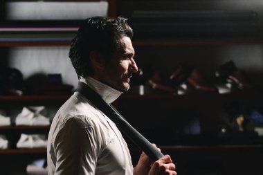 Terzi dükkanında terzi kıyafeti giyen bir adam takım elbise dener, kravatı düğümlenir ve onu çalışır halde tutar. Terzi, işadamı, zarafet kavramı.